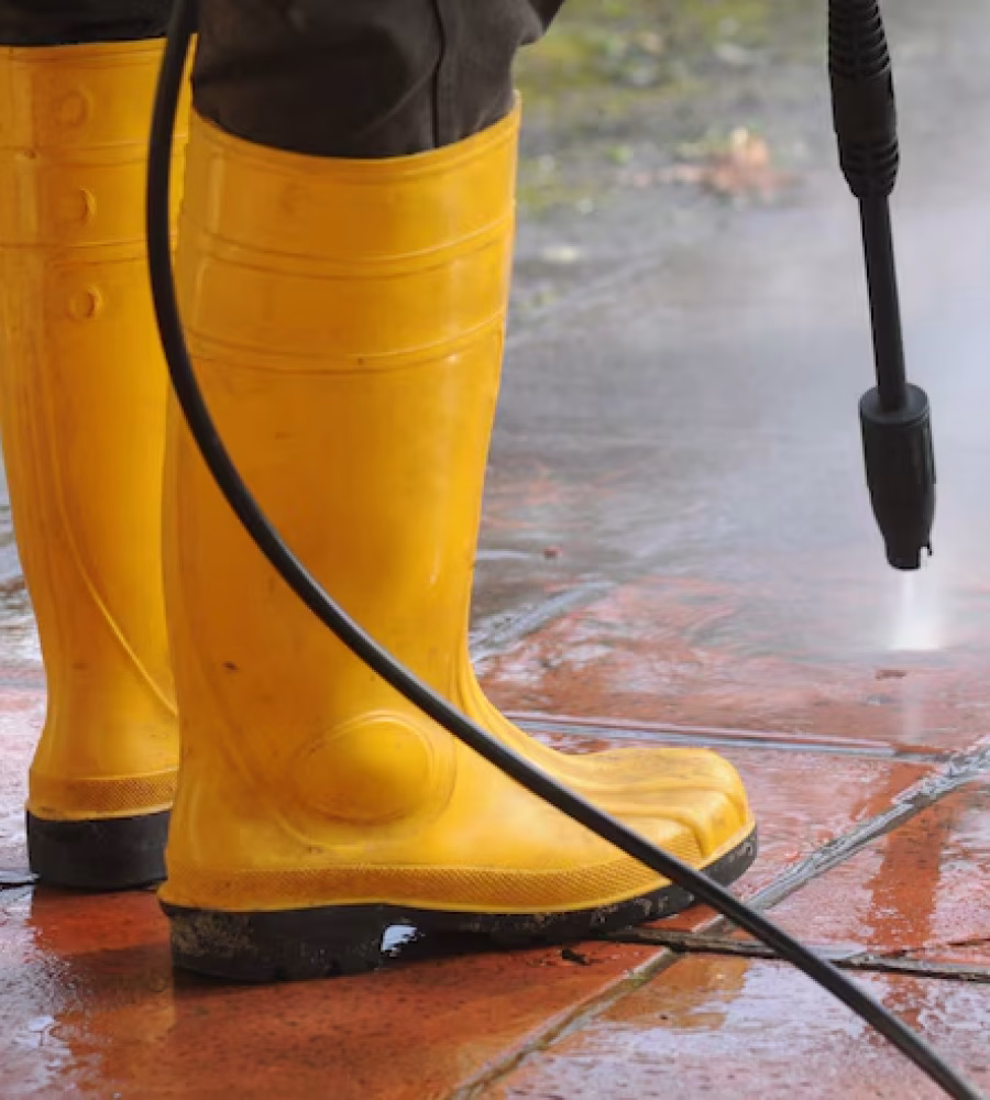 person-wearing-yellow-rubber-boots-with-high-pressure-water-nozzle-cleaning-dirt-tiles_181624-23652